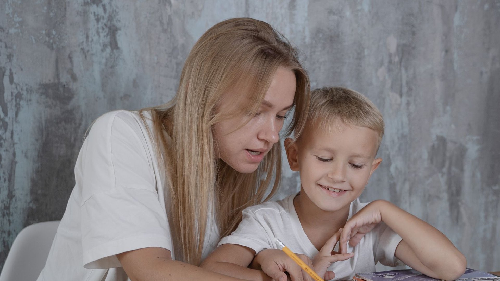 Mamá e hijo sonriendo mientras trabajan juntos en la mesa