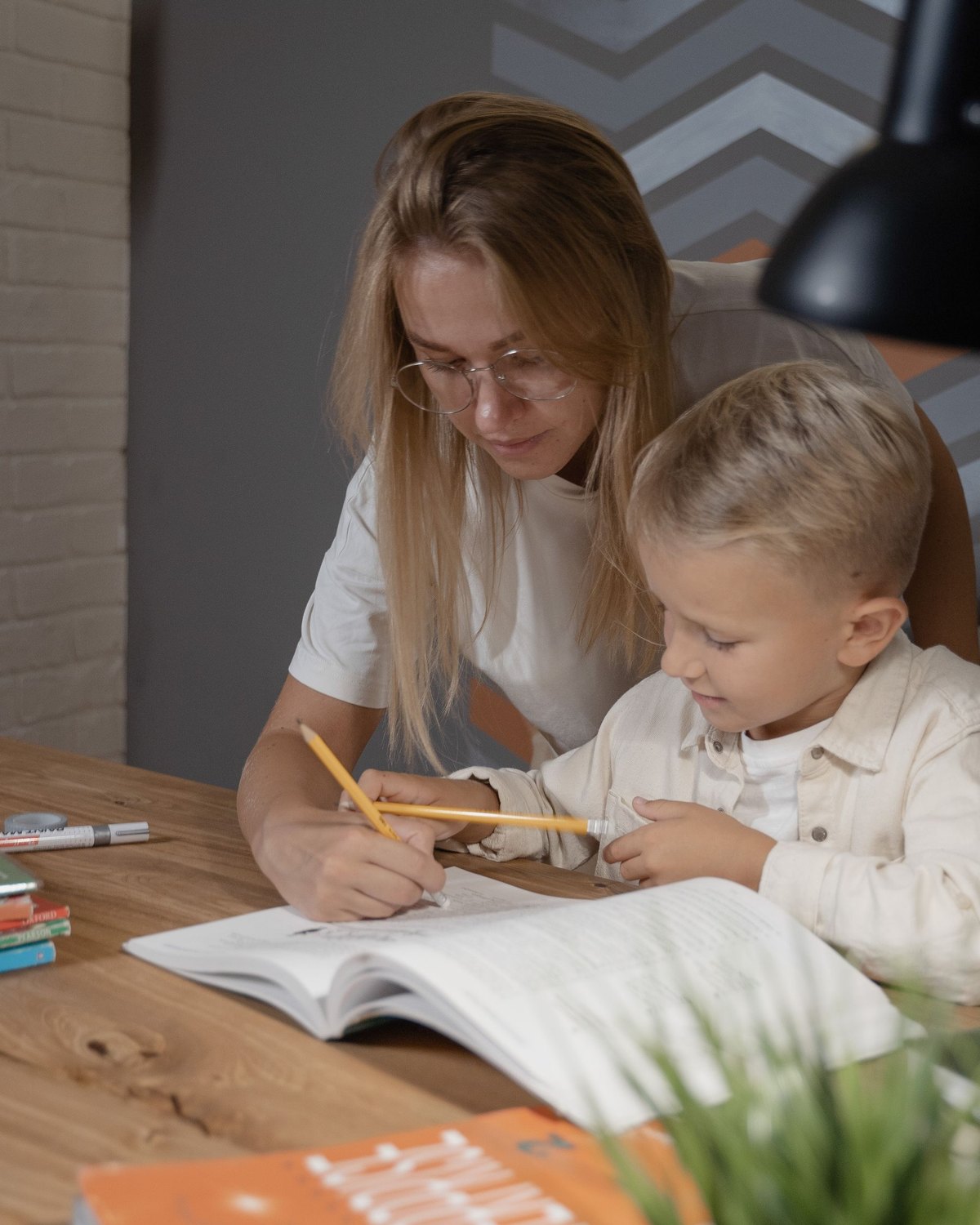 Niño escribiendo en su cuaderno junto a su mamá
